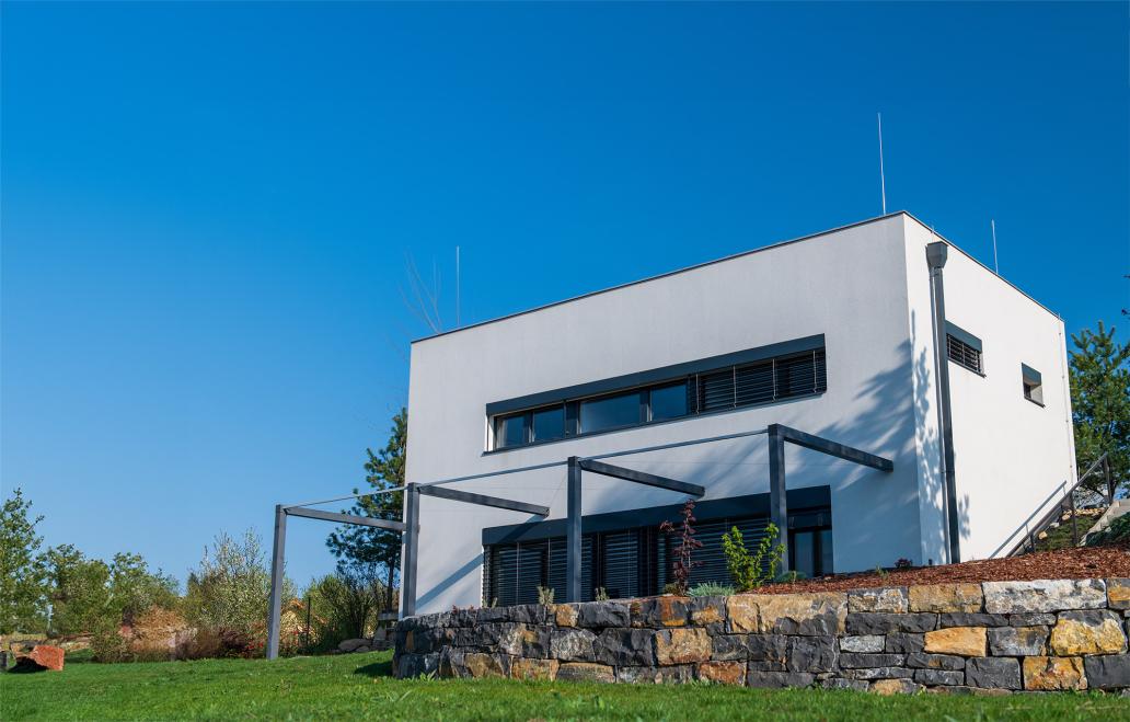 Modern, white, cube, elegant, minimalist style passive house with large panoramic windows, grey shutters in maintained garden