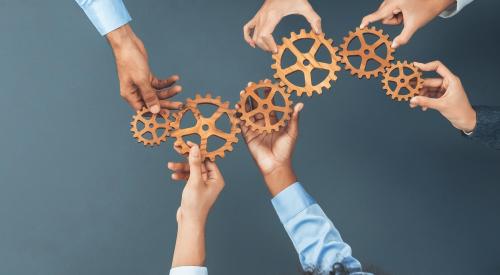 Hands holding together cogs for machine