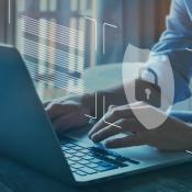 Businessman typing on laptop while padlock symbol floats in front of screen showing the concept of cybersecurity