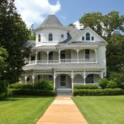 White victorian home sits on large lot lined with trees