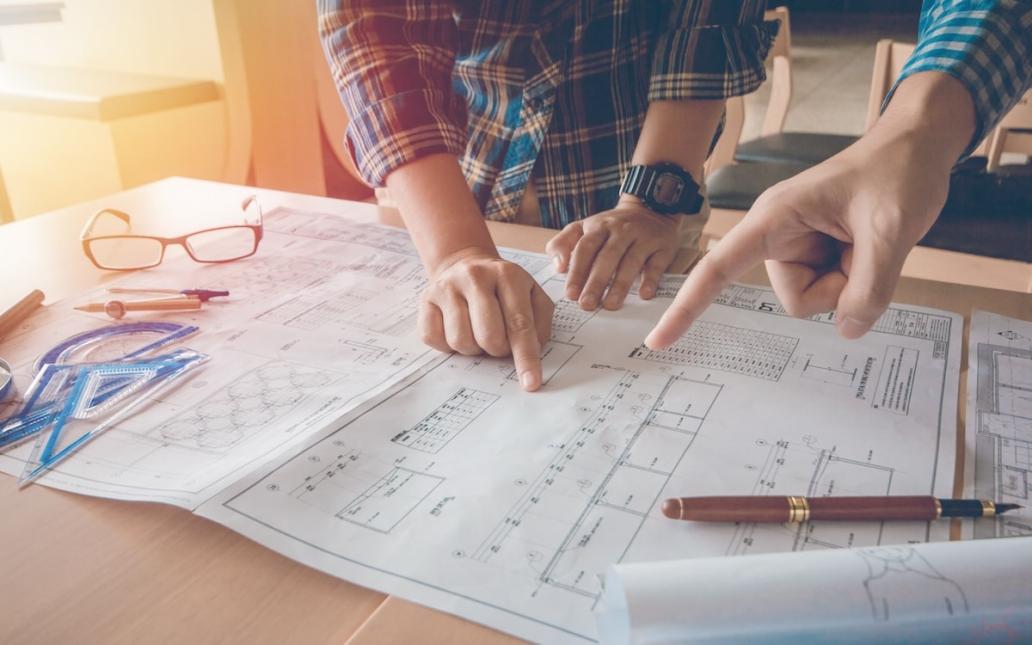 Two home builders look over plans on table