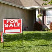 Single-family home with red "For Sale" sign on front lawn