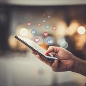 Close-up of hand using phone to post on social media