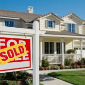 Sign reading "sold" sits on front lawn of home