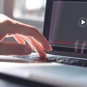 Close-up of hand pressing "play" on laptop to begin video