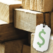 White price tag with green money symbol on stack of lumber